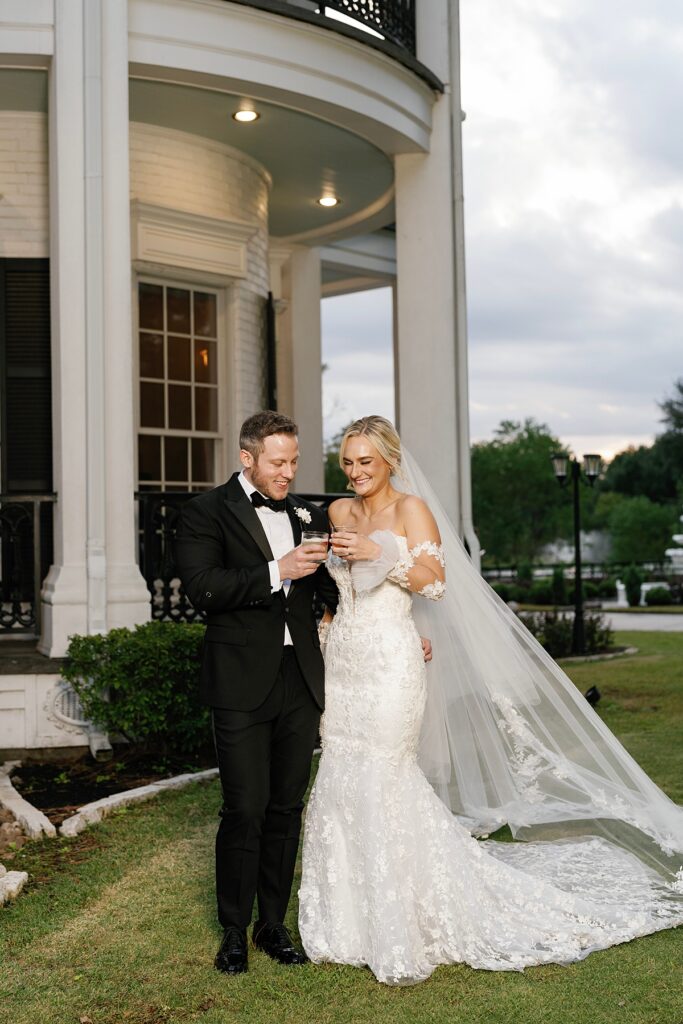 Bride and groom celebrating in front of Sandlewood Manor mansion