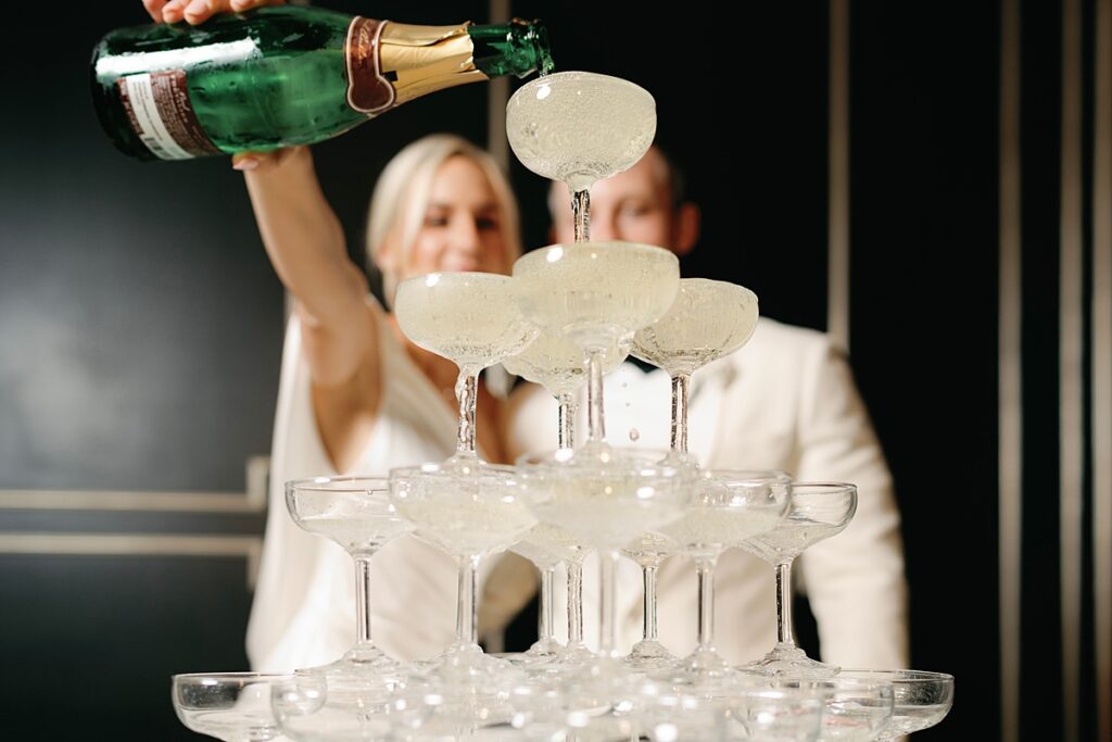 Bride and groom pouring champagne into tower at Sandlewood Manor reception